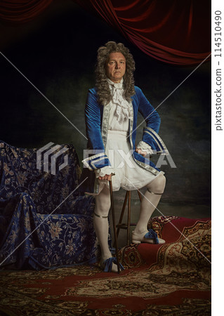 Portrait of elderly man dressed as medieval person, aristocrat with confident expression against vintage studio background. 114510490