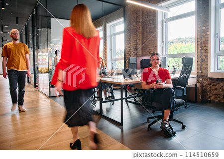 A diverse group of business professionals collaborates in a modern startup coworking center, utilizing a mix of paper-based and technological tools such as mobile phones and computers A diverse group of business professionals collaborates in a modern startup coworking center, utilizing a mix of paper-based and technological tools such as mobile phones and computers 114510659