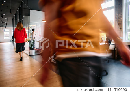 A diverse group of business professionals collaborates in a modern startup coworking center, utilizing a mix of paper-based and technological tools such as mobile phones and computers  114510690