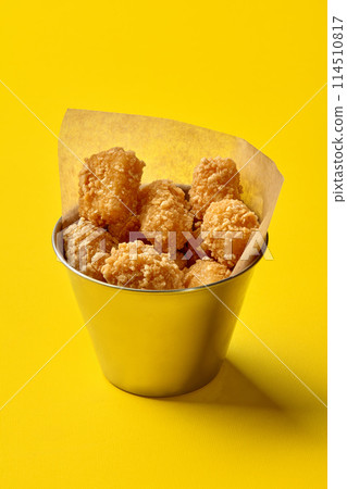 Metal bucket with chicken nuggets on yellow background 114510817