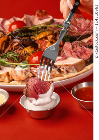Slice of roast beef on fork dipped into creamy sauce Slice of roast beef on fork dipped into creamy sauce 114510963