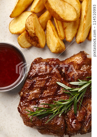 Juicy pork steak with potato wedges and barbecue sauce Juicy pork steak with potato wedges and barbecue sauce 114510993