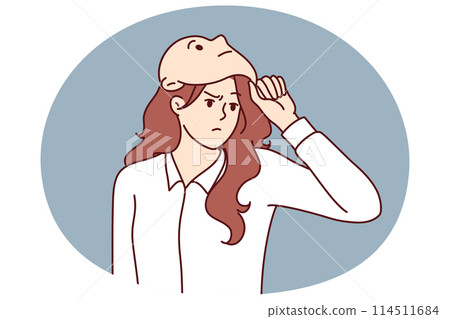 Frowning woman removes mask from face designed to hide identity or show fake emotions 114511684