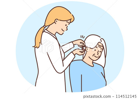 Female doctor install hearing aid to old patient 114512145