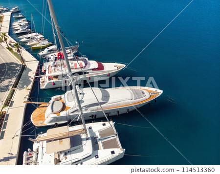 Scenic aerial view many yachts boats moored at Croatian bay harbor shore blue turquoise clear water at bright summer sunny day. Top above Mediterranean sea marina. Boat vessel charter service 114513360
