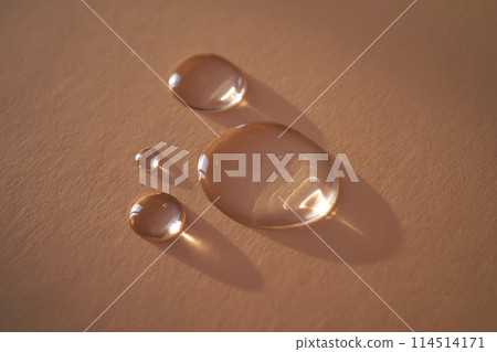 Beautiful volumetric drops of cosmetic product on a beige background. Beautiful volumetric drops of cosmetic product on a beige background. 114514171