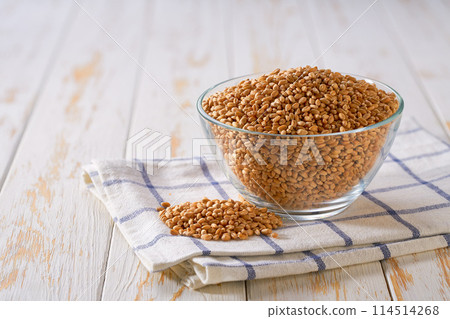 Raw organic wheats in a glass plate on a white wooden table. 114514268