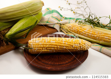 Clay plate with cob sweet corn on white wooden background.. 114515383