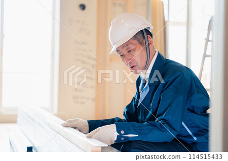 A carpenter checking materials at a construction site A carpenter checking materials at a construction site 114515433