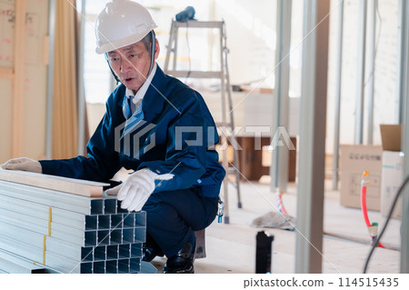 A carpenter checking materials at a construction site A carpenter checking materials at a construction site 114515435