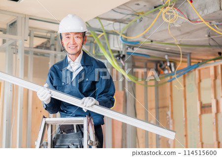 Carpenter carrying materials at a construction site Carpenter carrying materials at a construction site 114515600