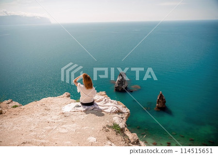 A woman is sitting on a rock overlooking the ocean. She is pointing to the water. The scene is peaceful and serene, with the woman enjoying the view and the calming sound of the waves. A woman is sitting on a rock overlooking the ocean. She is pointing to the water. The scene is peaceful and serene, with the woman enjoying the view and the calming sound of the waves. 114515651
