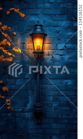 Illuminated Vintage Street Lamp on a Blue Brick Wall at Night 114516152