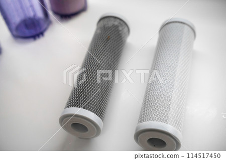New and used carbon filter for reverse osmosis purification water system on the table in the kitchen. New and used carbon filter for reverse osmosis purification water system on the table in the kitchen. 114517450