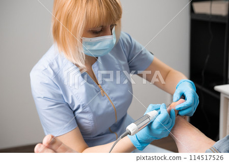 Portrait of podiatrist employs a milling machine for callus removal Portrait of podiatrist employs a milling machine for callus removal 114517526