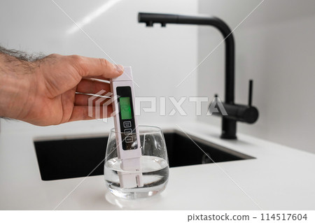 Man hand immerses TDS tester or conductometer into the water in glass. demonstrates that the water is clean. Man hand immerses TDS tester or conductometer into the water in glass. demonstrates that the water is clean. 114517604