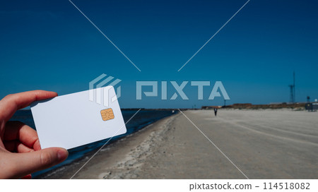 A person holding a white credit card on a beach A person holding a white credit card on a beach 114518082