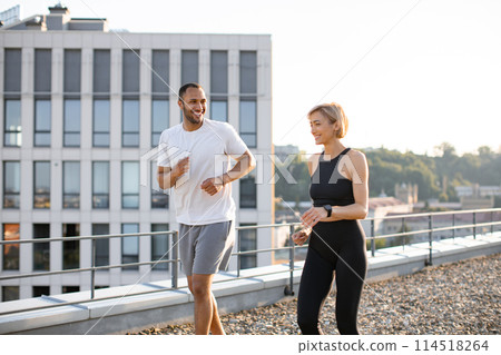 Young sports couple doing sports in morning on roof of modern building. 114518264