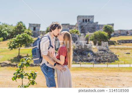 Couple man and woman tourists enjoying the view Pre-Columbian Mayan walled city of Tulum, Quintana Roo, Mexico, North America, Tulum, Mexico. El Castillo - castle the Mayan city of Tulum main temple 114518500