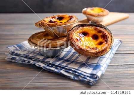 Custard tarts on a checkered cloth, wooden backdrop Custard tarts on a checkered cloth, wooden backdrop 114519151