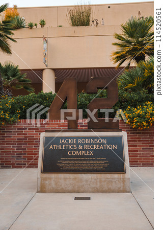 Number 42 prominently displayed in sports complex dedicated to Jackie Robinson, legend who broke color barrier in baseball. Building with balcony and palm trees, location unknown. 114520561