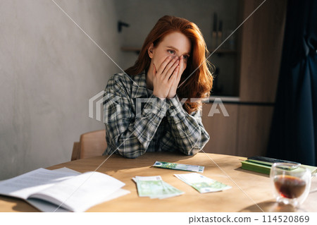Desperate young woman counting money with sad expression, sitting at home kitchen table. Sad female having financial literacy and loan repayment. Concept of financial crisis. Desperate young woman counting money with sad expression, sitting at home kitchen table. Sad female having financial literacy and loan repayment. Concept of financial crisis. 114520869