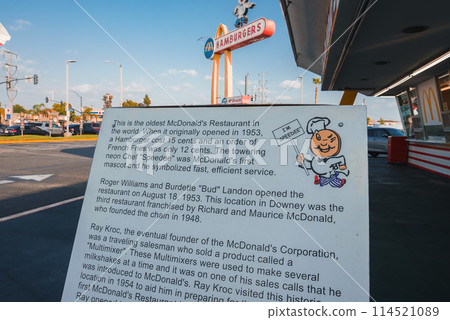 Historical marker at oldest McDonald's in Downey, California. Cartoon chef, iconic restaurant in background with golden arches. Sunny day, LA area landmark. 114521089