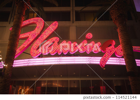 Neon sign of Flamingo Las Vegas Hotel and Casino, vibrant pink and white lights on the Strip. Retro neon aesthetic with palm trees and lively atmosphere captured. 114521144