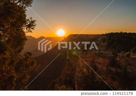 Scenic sunset at Grand Canyon with red rock layers glowing in golden light, vast horizon, and serene atmosphere. Ideal for nature and landscape enthusiasts. 114521179
