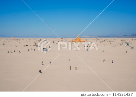 Discover a vibrant desert scene with a striking orange structure surrounded by festival attendees in a vast sandy landscape under a clear blue sky. Ideal for art and music festival concepts. Discover a vibrant desert scene with a striking orange structure surrounded by festival attendees in a vast sandy landscape under a clear blue sky. Ideal for art and music festival concepts. 114521427