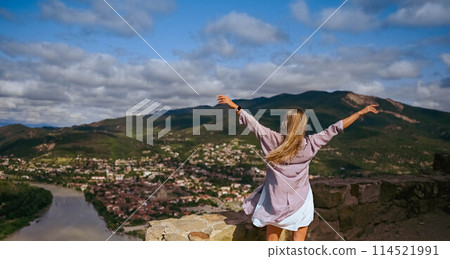 Young woman blonde tourist posing arms outstretched, confluence of two rivers Aragvi and Kura, ancient city Mtskheta, Georgia. Summer holiday vacation, active lifestyle freedom concept banner 114521991