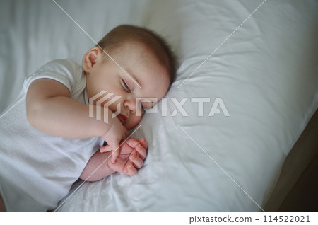 Cute funny newborn little boy peacefully sleeping on white sheets in bed or crib. Baby goods packaging template. Healthy child, concept of hospital and happy motherhood. Infant baby. Nursery Cute funny newborn little boy peacefully sleeping on white sheets in bed or crib. Baby goods packaging template. Healthy child, concept of hospital and happy motherhood. Infant baby. Nursery 114522021