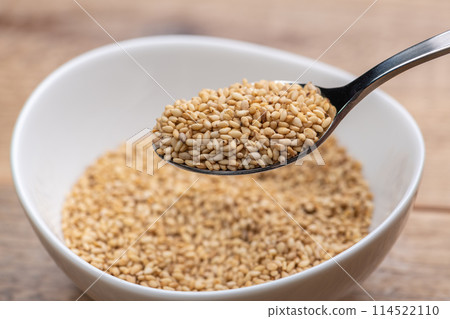 Scoop white sesame seeds with a spoon Scoop white sesame seeds with a spoon 114522110