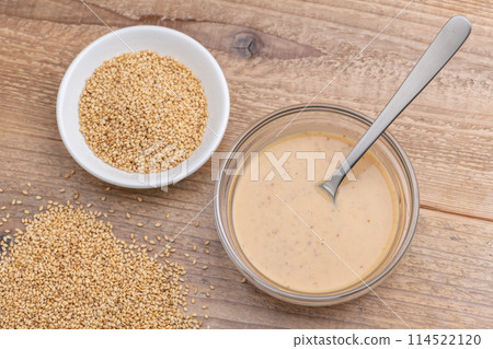 Overhead view of sesame sauce and white sesame seeds on a wooden table background Overhead view of sesame sauce and white sesame seeds on a wooden table background 114522120