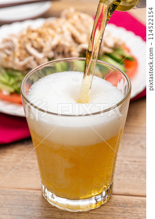 Beer poured into a glass and Bang Bang Chicken 114522154