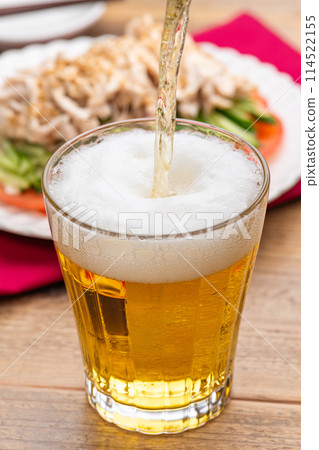 Beer poured into a glass and Bang Bang Chicken 114522155