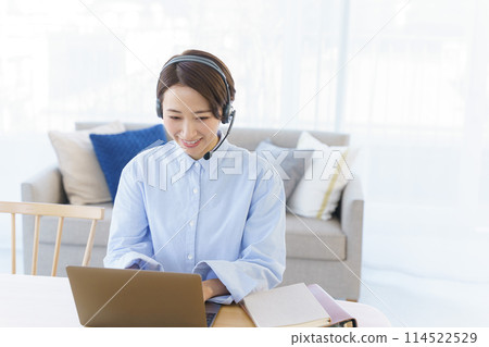 A woman teleworking in a room A woman teleworking in a room 114522529