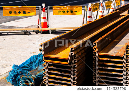 High contrast between road under construction and piled up steel materials High contrast between road under construction and piled up steel materials 114522798