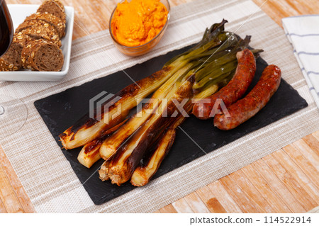 Traditional Spanish cuisine - Calsot con butifarra. Appetizer butifarra sausage and delicious calsot served on plate 114522914