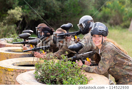 Group of paintball players aiming and shooting with guns Group of paintball players aiming and shooting with guns 114522930