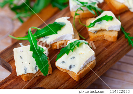 Freshly prepared sandwiches with blue cheese and green arugula on wooden board Freshly prepared sandwiches with blue cheese and green arugula on wooden board 114522933