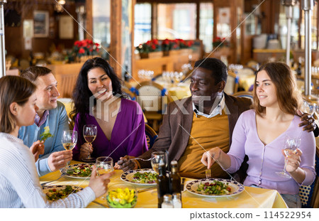 Group of joyous friends enjoying evening meal at restaurant Group of joyous friends enjoying evening meal at restaurant 114522954