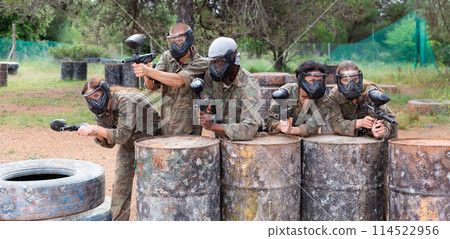 Group of paintball players aiming and shooting with guns Group of paintball players aiming and shooting with guns 114522956
