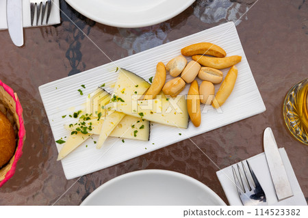 Slices of semi-hard spanish manchego sheep cheese sprinkled with chopped herbs and crutones at plate Slices of semi-hard spanish manchego sheep cheese sprinkled with chopped herbs and crutones at plate 114523382