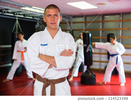 Man in kimono during group karate training Man in kimono during group karate training 114523399