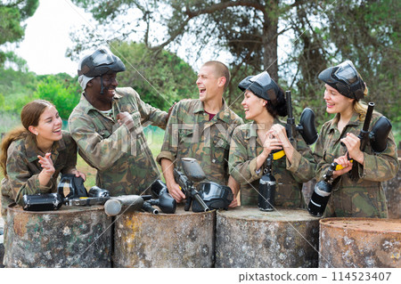 Smiling friends chatting after successful paintball match 114523407