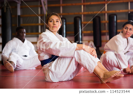 Man and woman in kimono warming up before karate training. They're doing stretching exercises for legs 114523544
