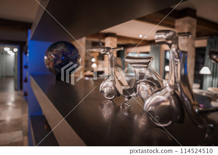 Luxury camel sculpture on wood shelf with colorful glass globe, Zermatt ski resort hotel decor with warm, elegant lighting and rustic design, Switzerland. 114524510