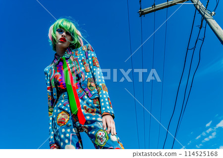 A woman in a green wig and a blue suit with a green tie poses for a photo 114525168