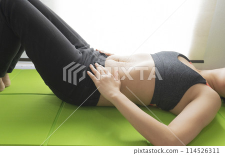 一位女士仰躺在瑜珈墊上，腹部有產後妊娠紋 114526311